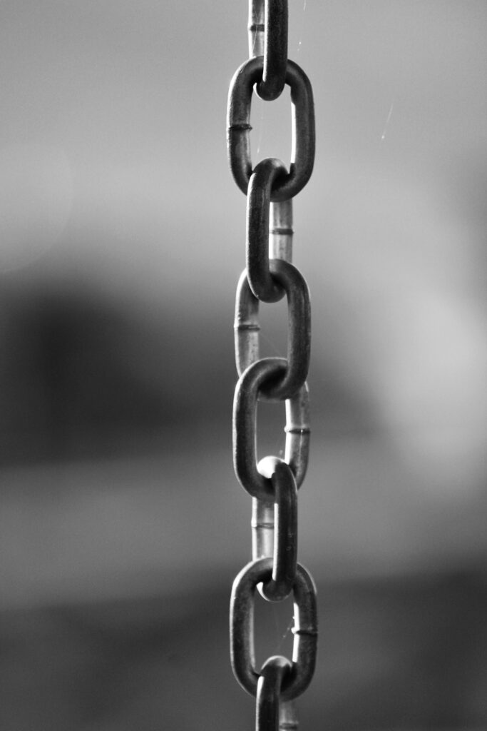 Artistic black and white close-up of a metal chain with shallow depth of field.