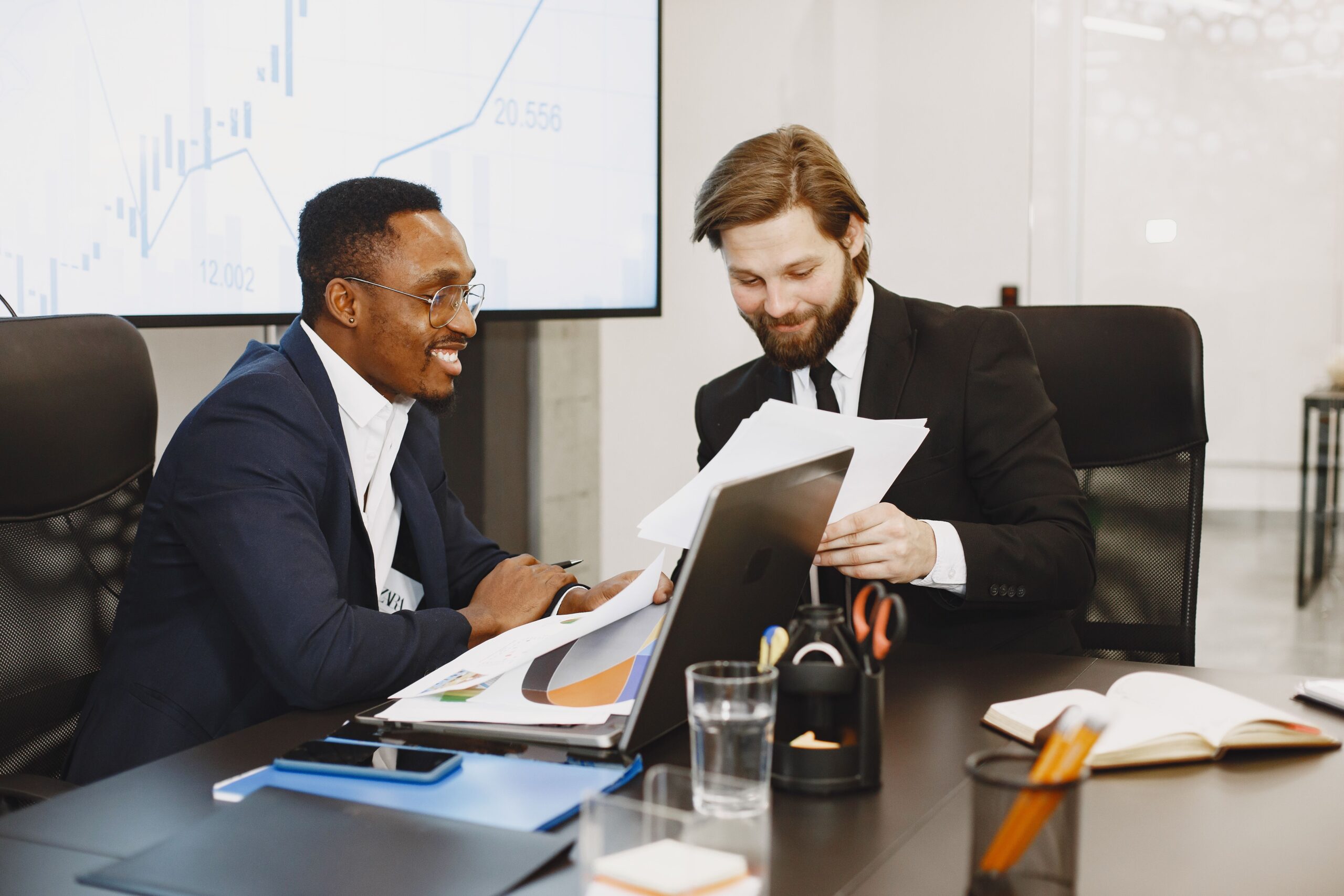 Two businessmen discussing documents in a modern office, fostering teamwork.